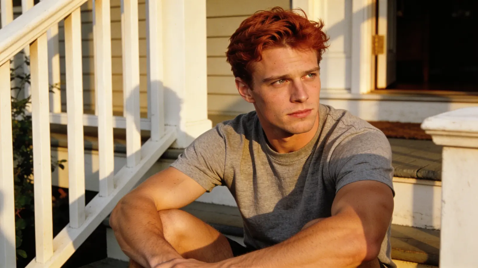 Young man sitting on a porch step in warm afternoon light, reflective